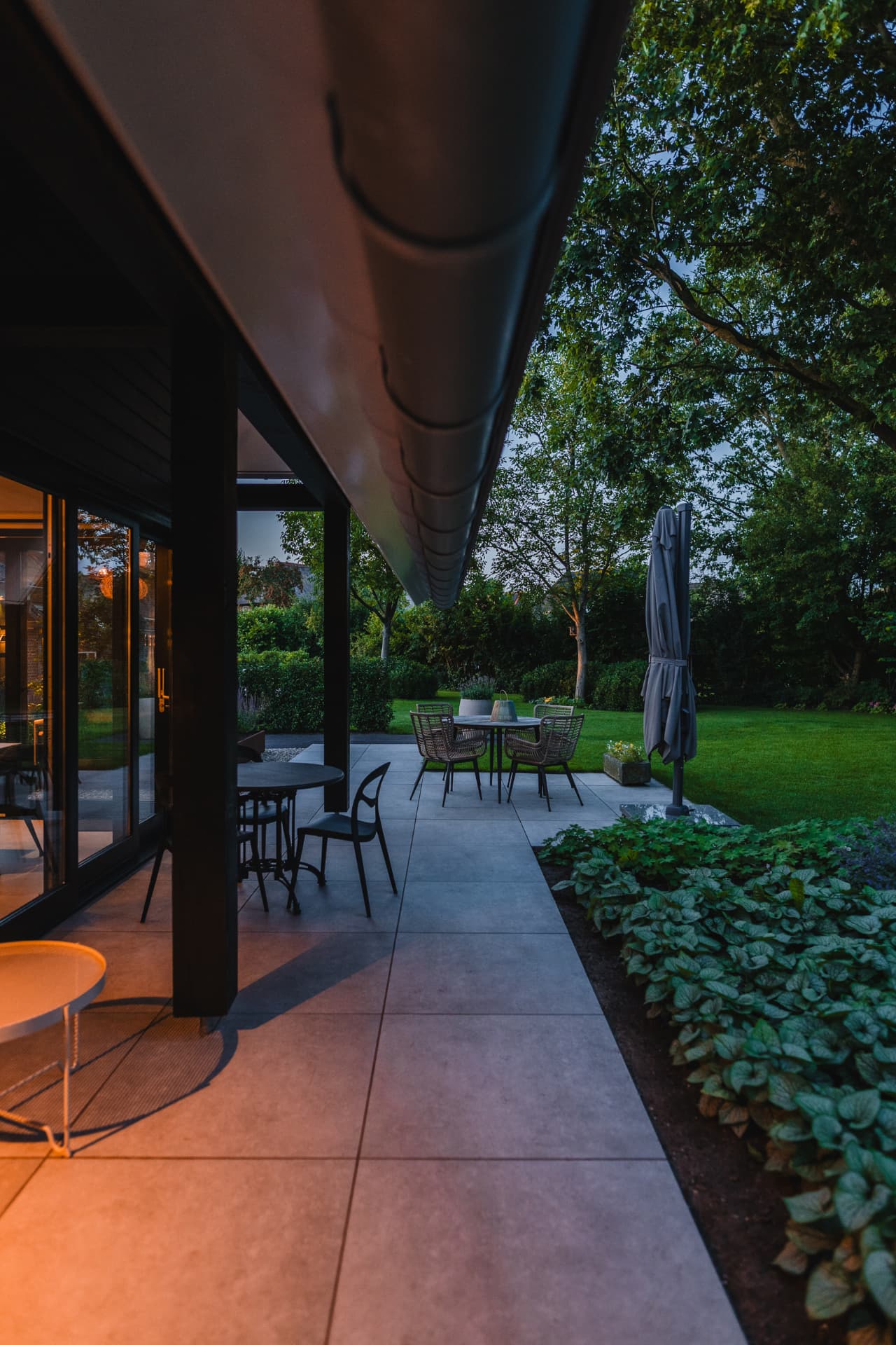 Overdekt terras bij avondlicht, met uitzicht op de tuin